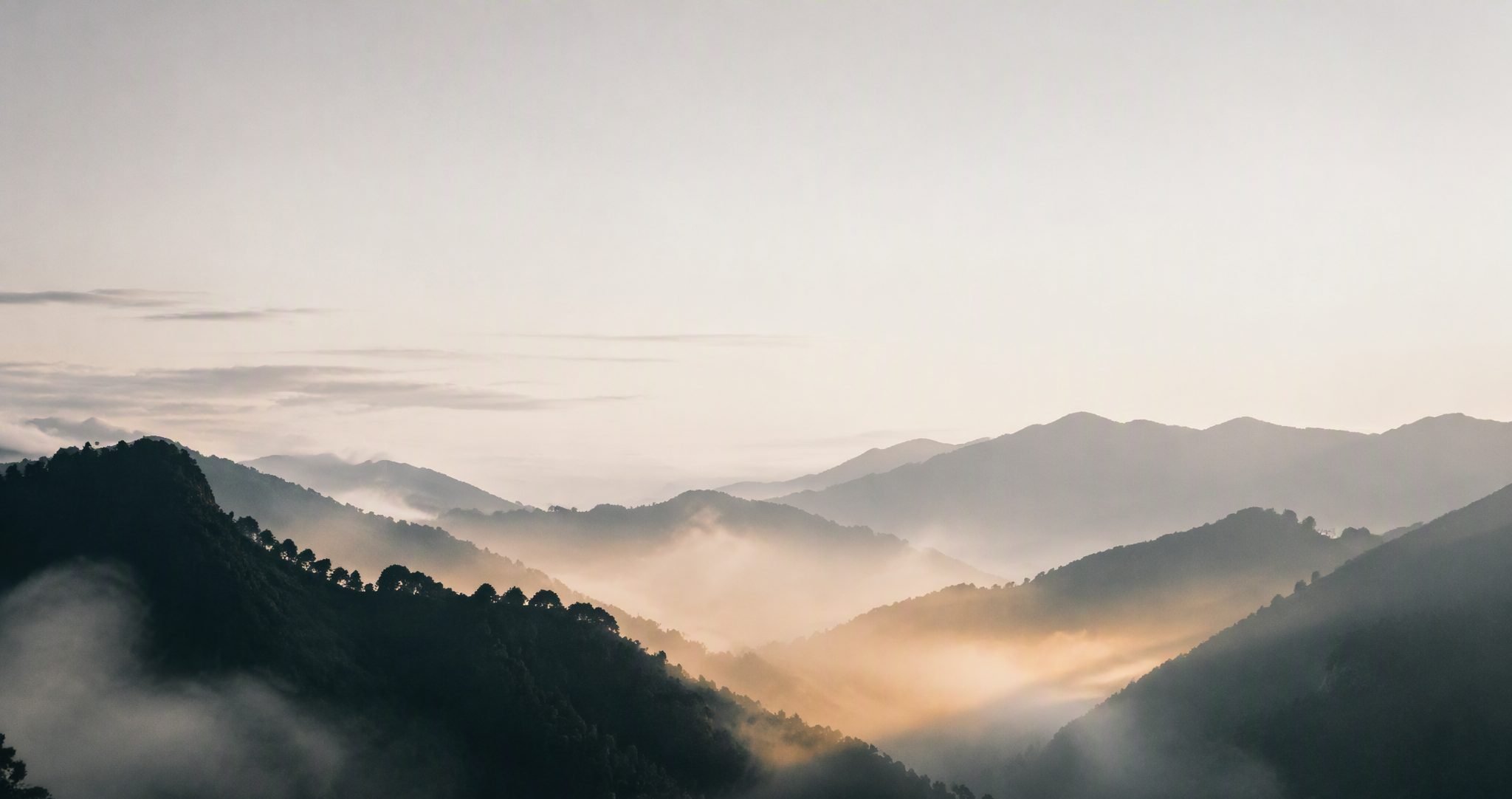 晨霧繚繞的山巒，晨光自山谷間升起